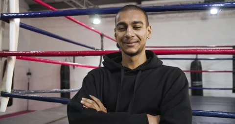 Camera pushing in while man crossing arms in boxing ring near punching bag Stock Footage 335624343