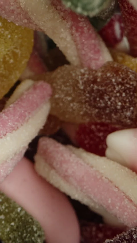The camera quickly ascends from the glass of assorted gummy candies dusted with Stock Footage 249571644