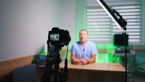 Camera records a video of a man sitting at desk in the room. Caucasian doctor Stock Footage 333782620