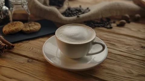 The camera revolves around a cup of coffee taken by an unrecognizable woman Stock Footage 127797285