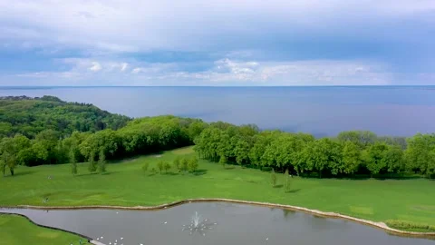 The camera rises above the pond in which swans swim against the backdrop of fore Stock Footage 156964539