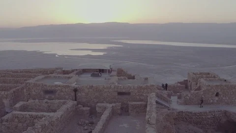 Camera rises above rocks to show sunrise over ancient city Stock Footage 82836728
