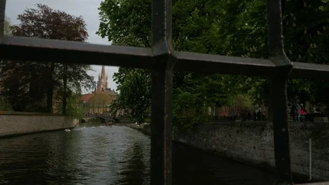 Camera rises behind railings to reveal Dijver canal and Our Lady Church Stock Footage 90454877