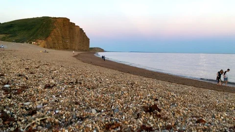 Camera rises jib style over the beach and cliffs in West Bay Stock Footage 94364227