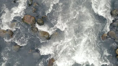 The camera rises straight up over a cold shallow mountain stream. A stormy Vidéo 153674398