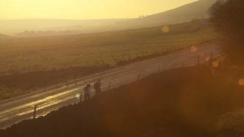 Camera rises up as two hikers walk toward sunset in beautiful landscape Stock Footage 105304123