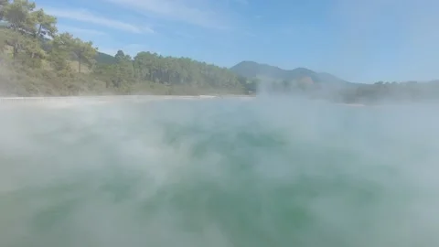 Camera rising and submersing into the clouds above hot steaming pond. Video stock 182885114