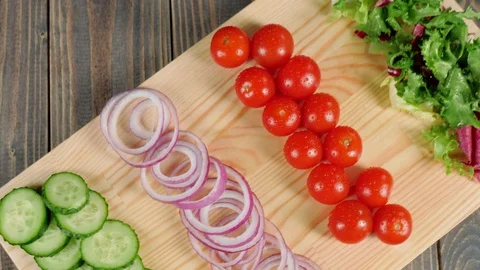 Camera rotates above fresh cucumbers, onions, cherry tomatoes and lettuce Stock Footage 129746100