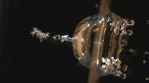 Camera rotates as champagne colored water is poured against black background Stock Footage 63850194