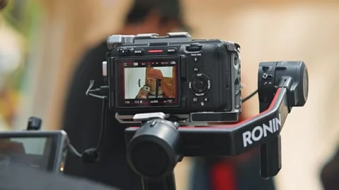 A camera is set on a stabilizer, filming a person in an outdoor environment. The Stock Footage 345036030