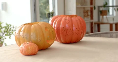 Camera is shifting as daylight is settling over three pumpkins on beige table, Video stock 346179504