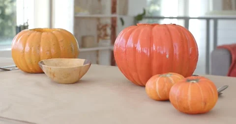 Camera is shifting focus and exposure, revealing glossy orange pumpkins on table Stock Footage 346709320