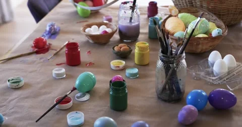 Camera is shifting focus to highlight brush jar, paint jars and pastel eggs on Stock Footage 341736545