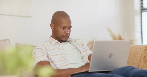 Camera shifting focus from potted plant, man typing on silver laptop, working on Stock Footage 337400548