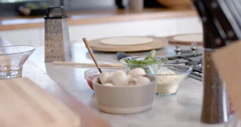 Camera is shifting focus to reveal grey bowl of mushrooms and prep bowls on Stock Footage 346709122