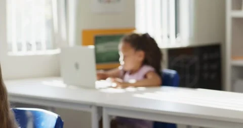 Camera shifting focus is revealing curly-haired girl typing on laptop in class Stock Footage 337705280