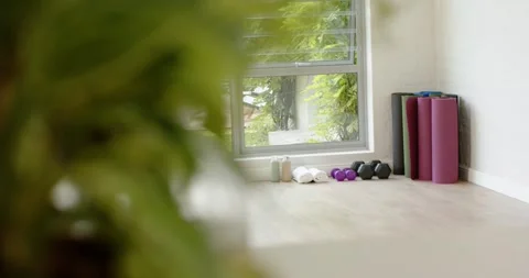 Camera is shifting focus, revealing stacked yoga mats, dumbbells and water Stock Footage 344384410