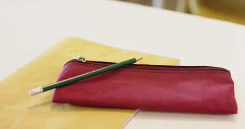 Camera is shifting focus on white table to emphasize red zippered pouch with Stock Footage 344333520