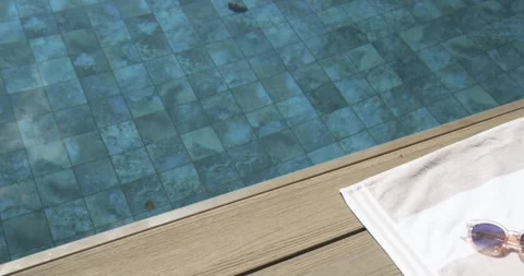 Camera is shifting right to reveal white towel with round sunglasses while pool Stock Footage 339321054