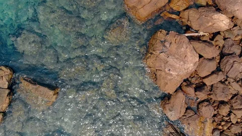 Camera shoots perfect clear blue ocean with huge wet stones Vidéo 111857199