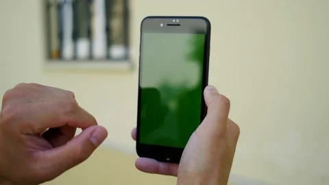 Camera shot of black phone with vertical green mock -up screen in male hand whic Stock Footage 112354665