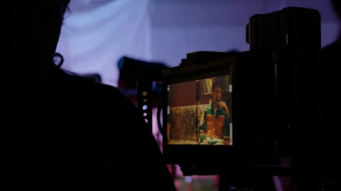 Camera shows actor on screen while crew members cross behind Stock Footage 308935732