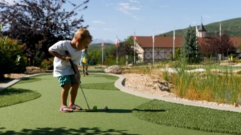 Camera shows the blond boy as he plays the mini golf Stockbeeldmateriaal 119126835