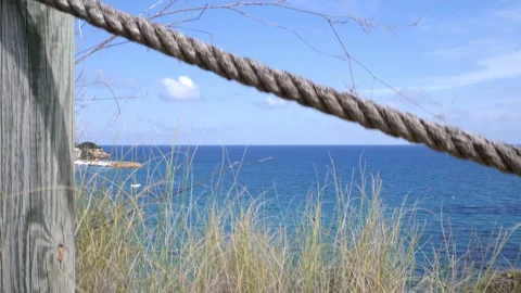 The camera shows grass, then a rope and then the whole bay by the sea. Stock Footage 152856236