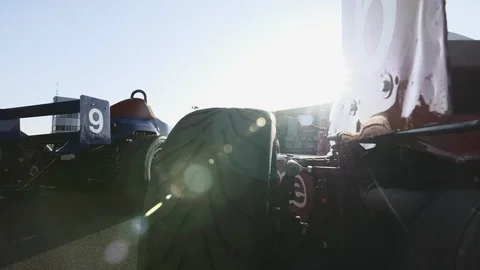 CAMERA SLIDE ON BACK OF PARKED RACE CARS WITH LENS FLARES 動画素材 127403998