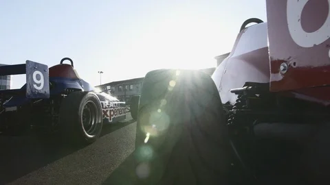 CAMERA SLIDE ON BACK OF PARKED RACE CARS WITH LENS FLARES 2 스톡 동영상 127404089