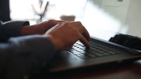 Camera slides around freelancer's hands typing on laptop keyboard in slow motion Video stock 84859020