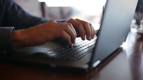 Camera slides around freelancer's hands typing on laptop keyboard in slow motion Stock Footage 84955087