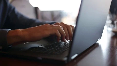 Camera slides around freelancer's hands typing on laptop keyboard in slow motion Stock Footage 84955112