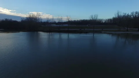 Camera sliding over river with trees on shore reflecting in water Stock Footage 60038754