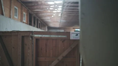 Camera sliding sideways revealing an old empty barn with wooden stables and a Video stock 332409907