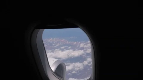 The camera slowly approaches the plane window showing a view of the clouds. Stock Footage 116125268