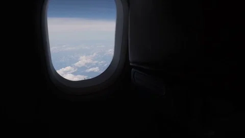 The camera slowly approaches the plane window showing a view of the clouds. Stock Footage 116125325