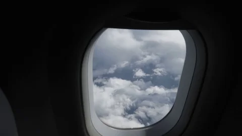 The camera slowly approaches the plane window showing a view of the clouds. Stock-Footage 117446072