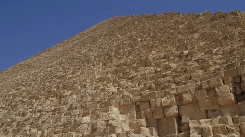 Camera slowly ascends with the awe-inspiring Great Pyramids of Giza. Video stock 254614892