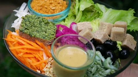 The camera slowly moves away from a large black glass salad bowl with vegetable Stock Footage 220748775