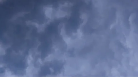 Camera slowly moves downward from gray, cloudy sky to ground, flies between Stock Footage 341284348