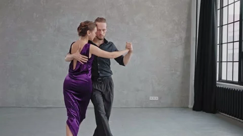 Camera slowly moving to a pair sensually dancing a tango in a grey studio 스톡 동영상 168630859