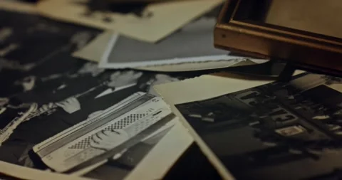 The camera slowly pans across a pile of old vintage black and white photos Stock Footage 256233555
