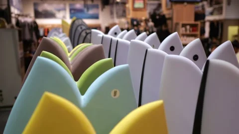 The camera slowly pans back, constantly in the frame is a row of surfboards in a Stock Footage 205588107