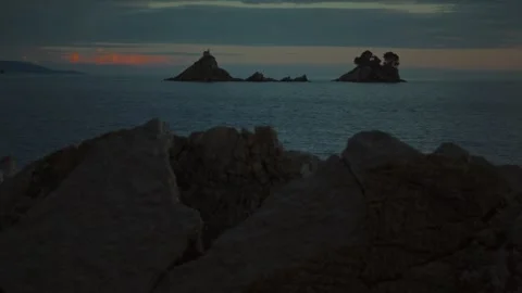 The camera slowly pans out from behind a coastal rock revealing a view of the Stock Footage 313731438
