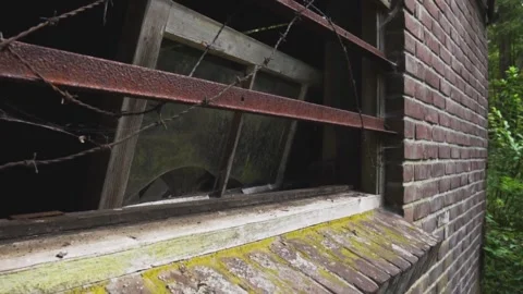 Camera slowly passing old broken window with barbed wire Stock Footage 292528777