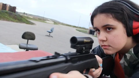 Camera slowly pulls in on young girl prepared to fire weapon Stock Footage 113912923