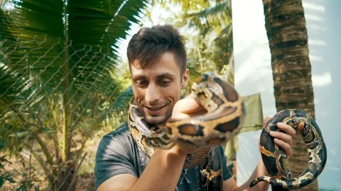 Camera slowly rotates around an attractive young male tourist holding a Burmese 库存影片 87207614