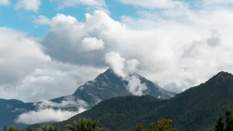 Camera slowly zoom in to mountain peak. Time lapse of clouds flying over Vídeo Stock 230008554