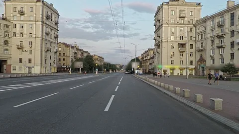 Camera smoothly cross the wide empty street of the evening city Stock Footage